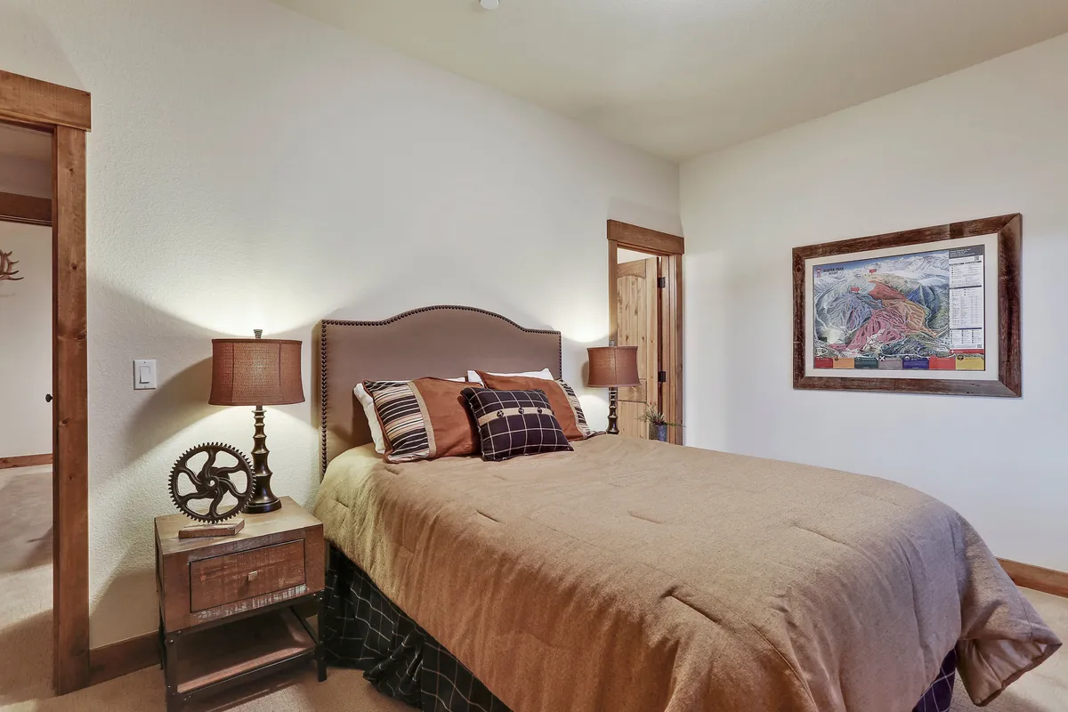 A cozy bedroom with a comfortable bed, soft bedding, matching side tables, elegant lamps, and soothing artwork above the headboard. The room is bathed in gentle light, creating a warm and restful atmosphere ideal for relaxation and sleep.