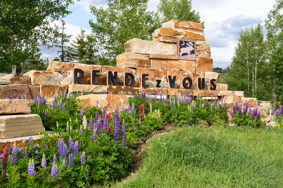 A welcoming exterior view featuring a stone sign, vibrant flower beds, and well-maintained landscaping. The scene gives a sense of arrival, emphasizing the villa's inviting presence and connection to the outdoors.