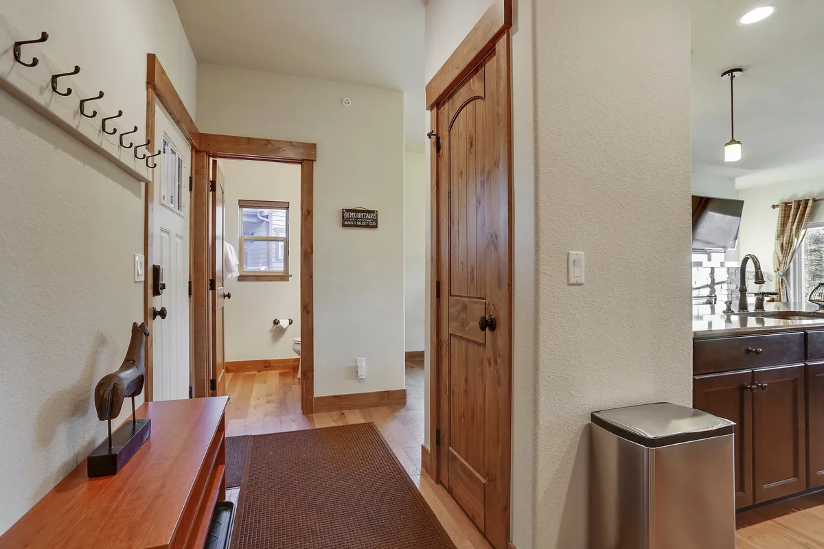 A mudroom with a coat rack, wooden bench, and a doorway leading further into the home, designed for greeting guests and storing outdoor gear after a day’s activities.